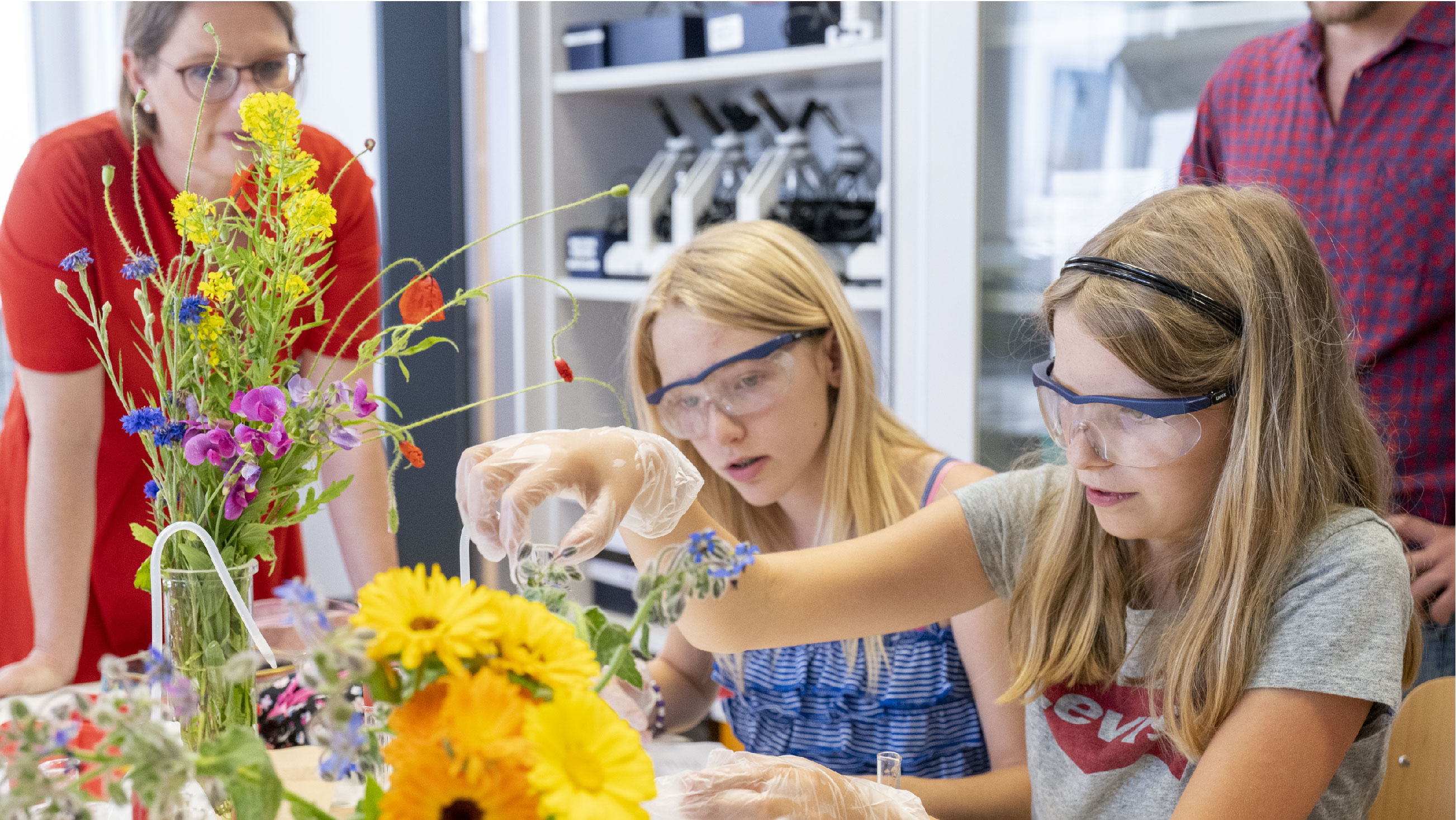 Bildungsministerin Dr. Stefanie Hubig schaut Schülerinnen beim Experimentieren über die Schulter. Foto/©: Stefan F. Sämmer, JGU